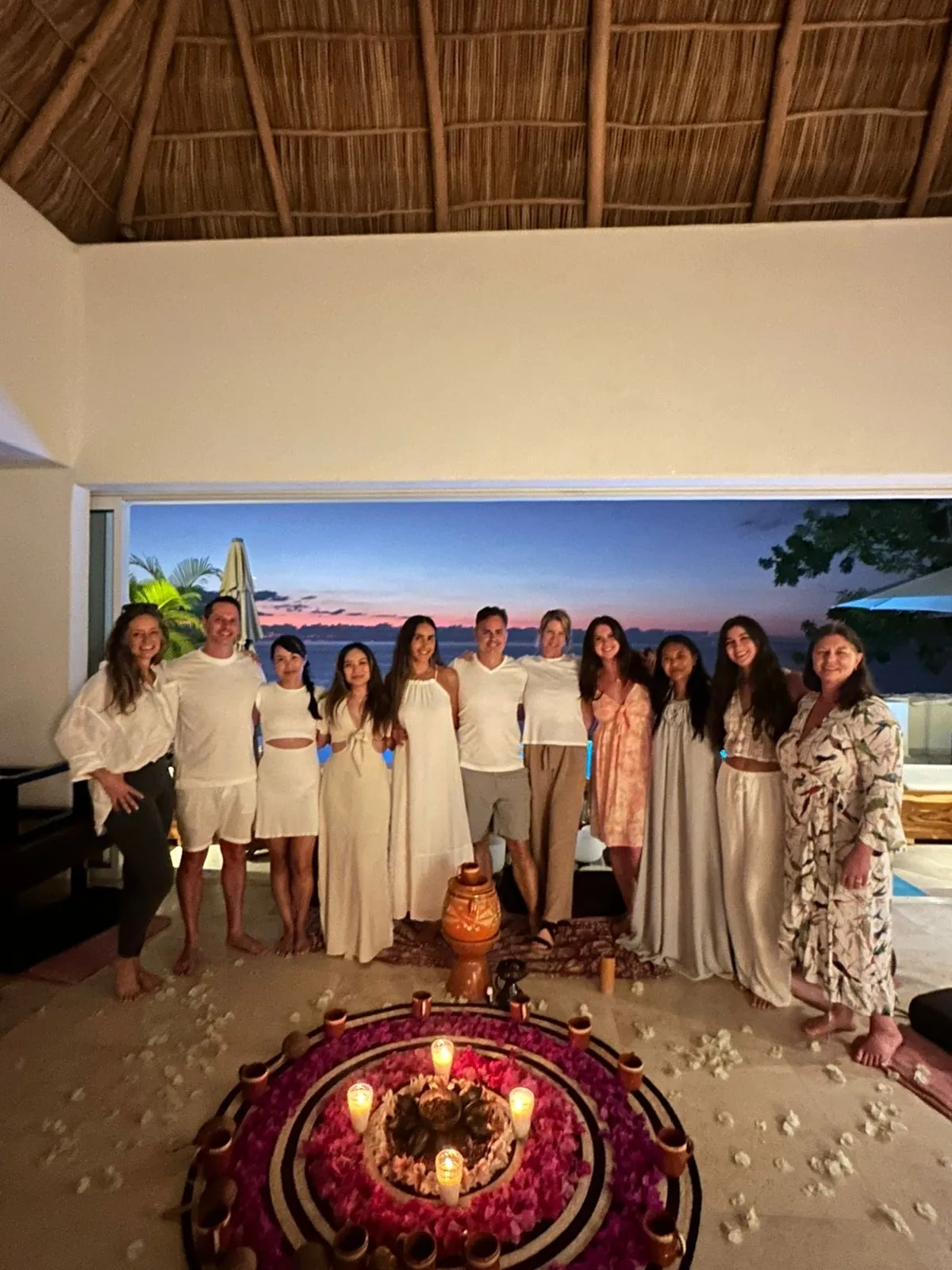 Group dressed in white around a candlelit flower mandala