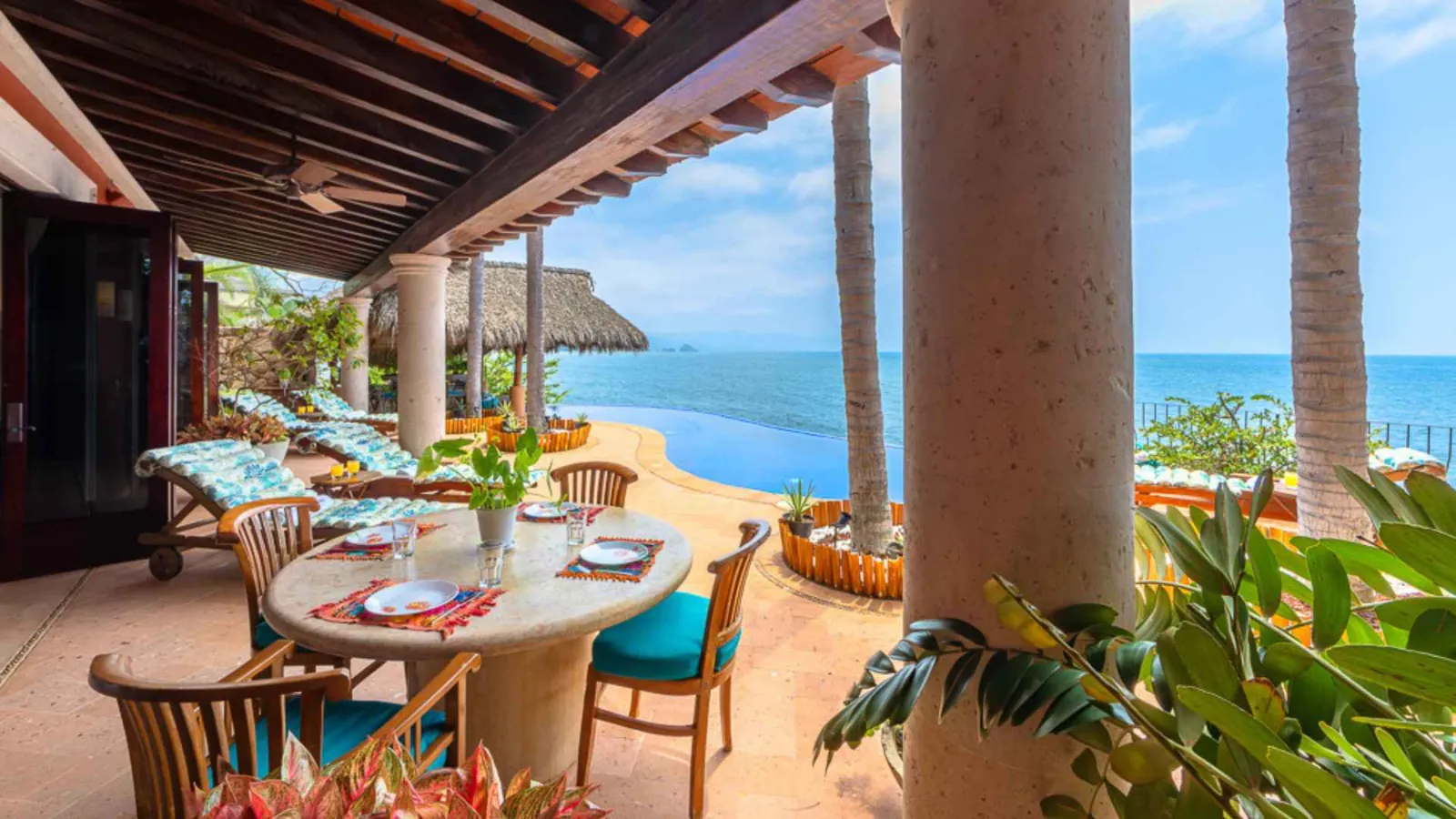 Poolside dining table set under the terrace with turquoise chairs