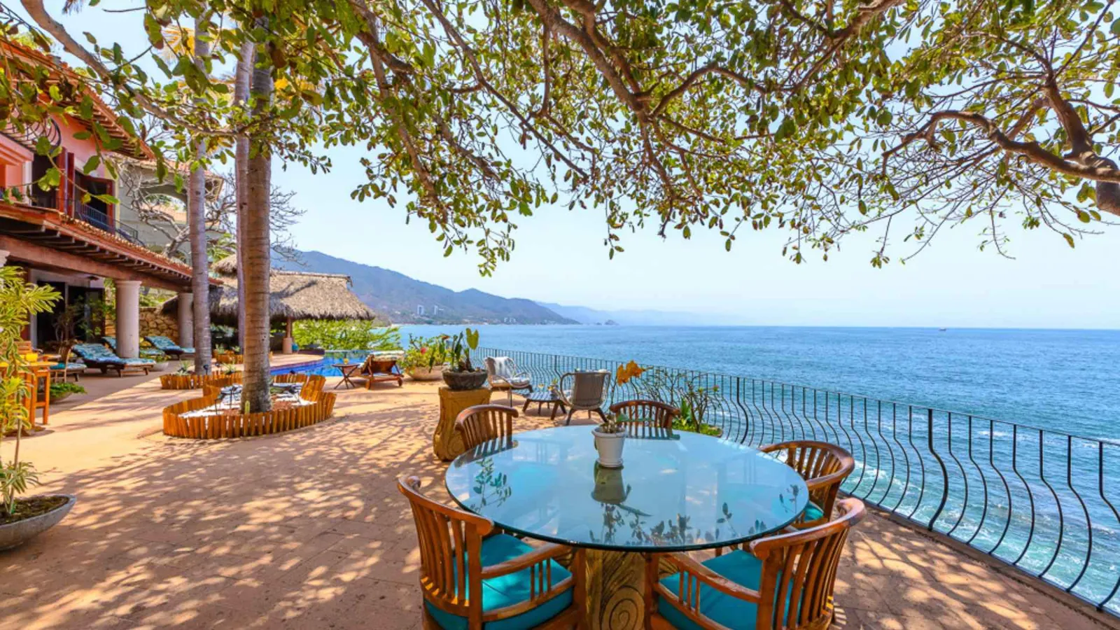 Shaded ocean-view terrace with a round table under the trees